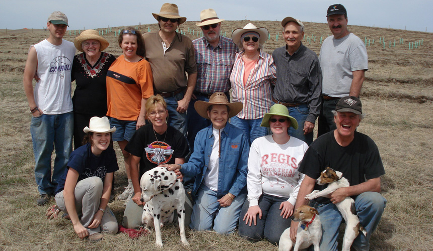The Gould family and the first planting crew with two dogs on the bare prairie